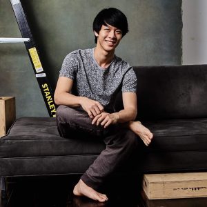 Andy Zou seated on couch with a ladder in the background