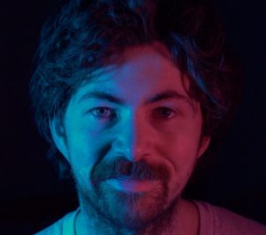 Geoffrey Stevens in blue and red light on a black background