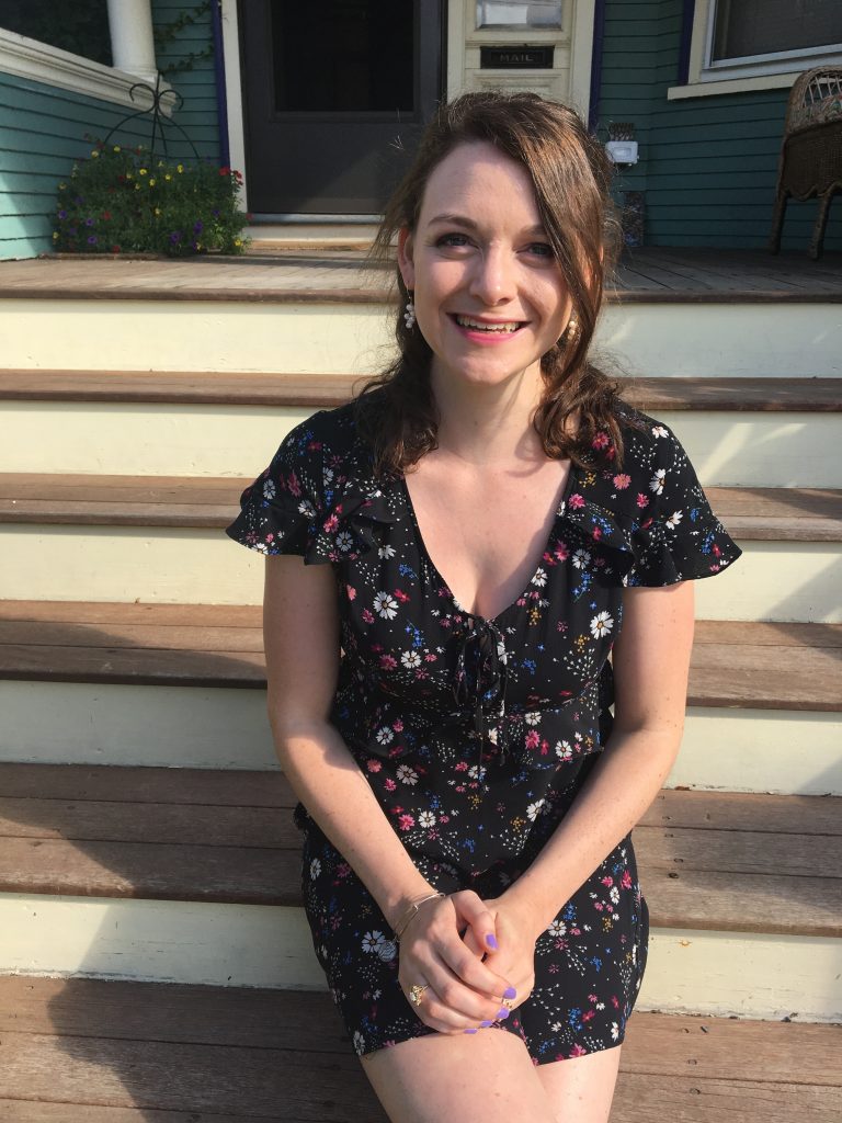 Robin McNamara in a dress sitting on some stairs